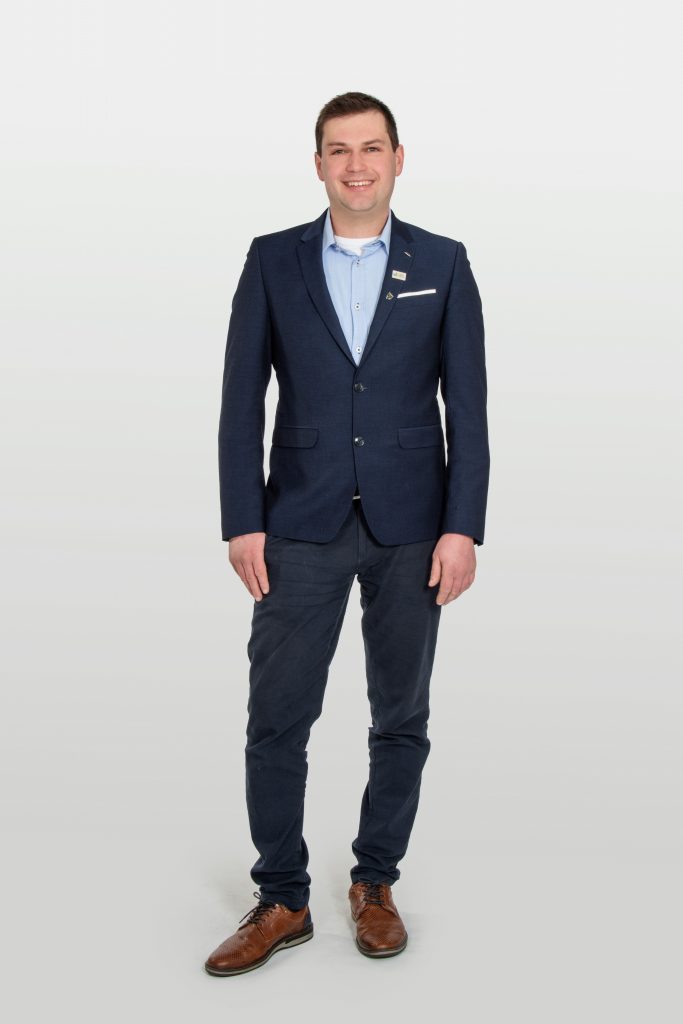 Mathias Flory in dunkelblauem Anzug steht vor hellem Hintergrund