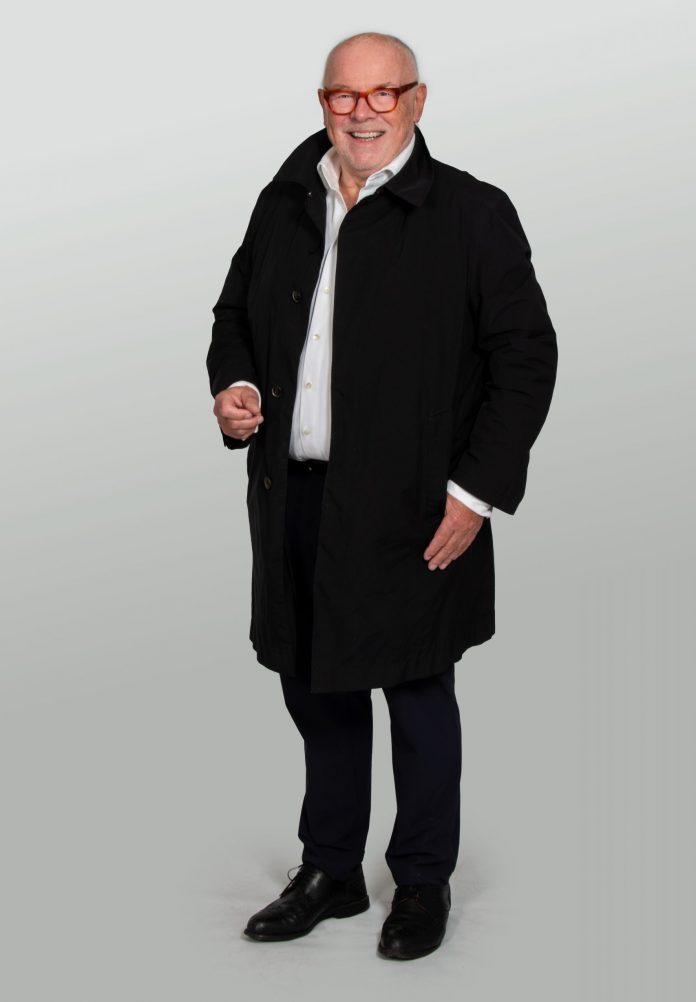 Thomas W. Schmidt steht im offenen Mantel vor hellem Hintergrund