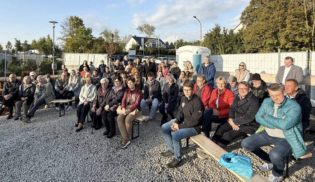 Viele Besucher sitzen auf der Baustelle und verfolgen die Grundsteinlegung des neuen Hotelkomplexes in Bad Windsheim