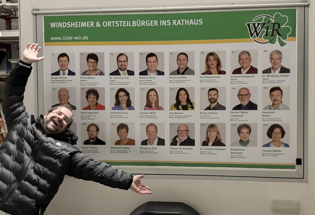 Dr. Christian Enz vor dem Großflächenplakat der Stadtratskandidaten auf dem Wahlkampf-Anhänger