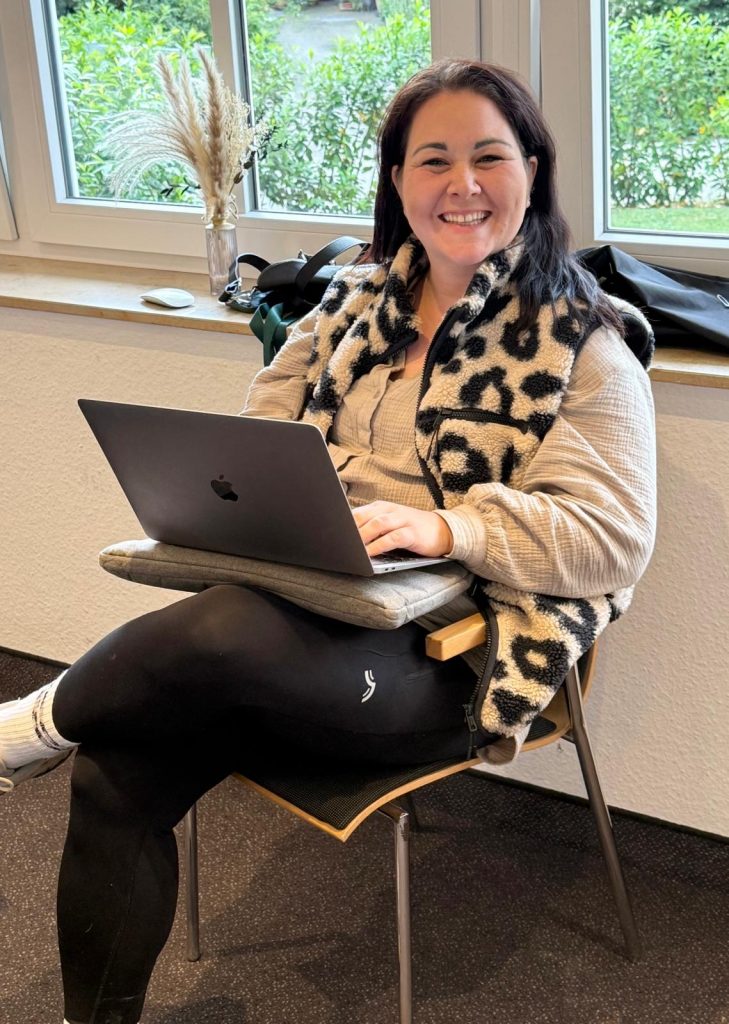 Lisa Bavosa sitzt auf einem Stuhl mit Laptop auf dem Schoß