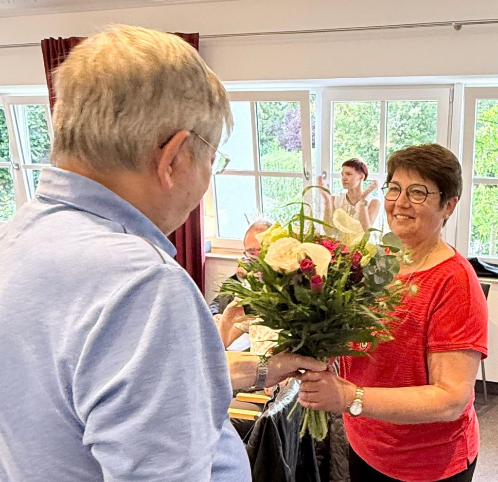 Gerhard Koslowski übergibt einen Blumenstrauß an Erika Löblein